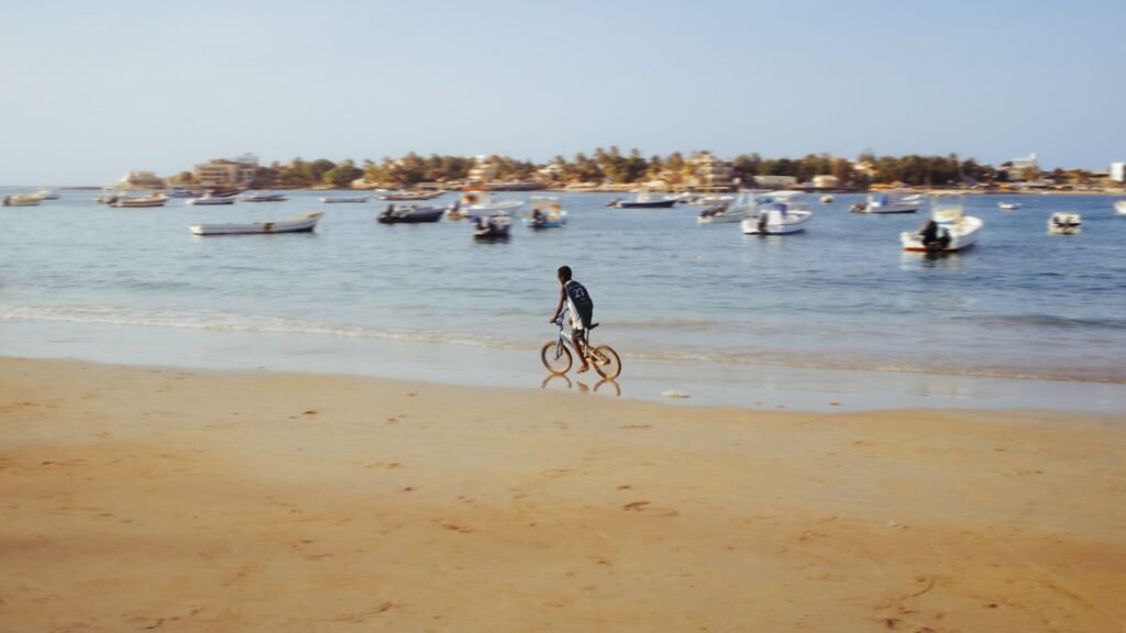 a man riding a bike on top of a sandy beach