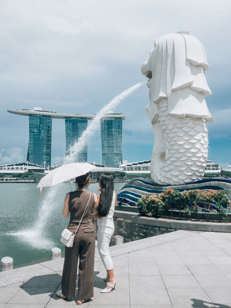 Two women observe the merlion statue spitting water in singapore